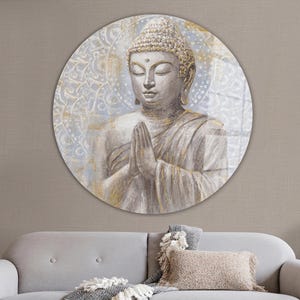 Puede incluir: Una pieza de arte de pared circular que presenta una estatua dorada de Buda con un fondo de mandala blanco y dorado. El Buda se representa con los ojos cerrados y las manos en posición de oración.