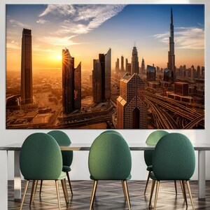 May include: A canvas print depicting a cityscape at sunset, with numerous skyscrapers and a highway. The sun is prominent in the image. The print is displayed above a dining table with green chairs.
