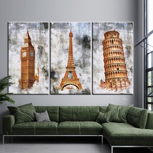 May include: A triptych canvas art print featuring iconic landmarks: Big Ben, the Eiffel Tower, and the Leaning Tower of Pisa. The artwork has a watercolor effect with gold and brown tones against a textured gray background. The canvas is displayed above a green sectional sofa.