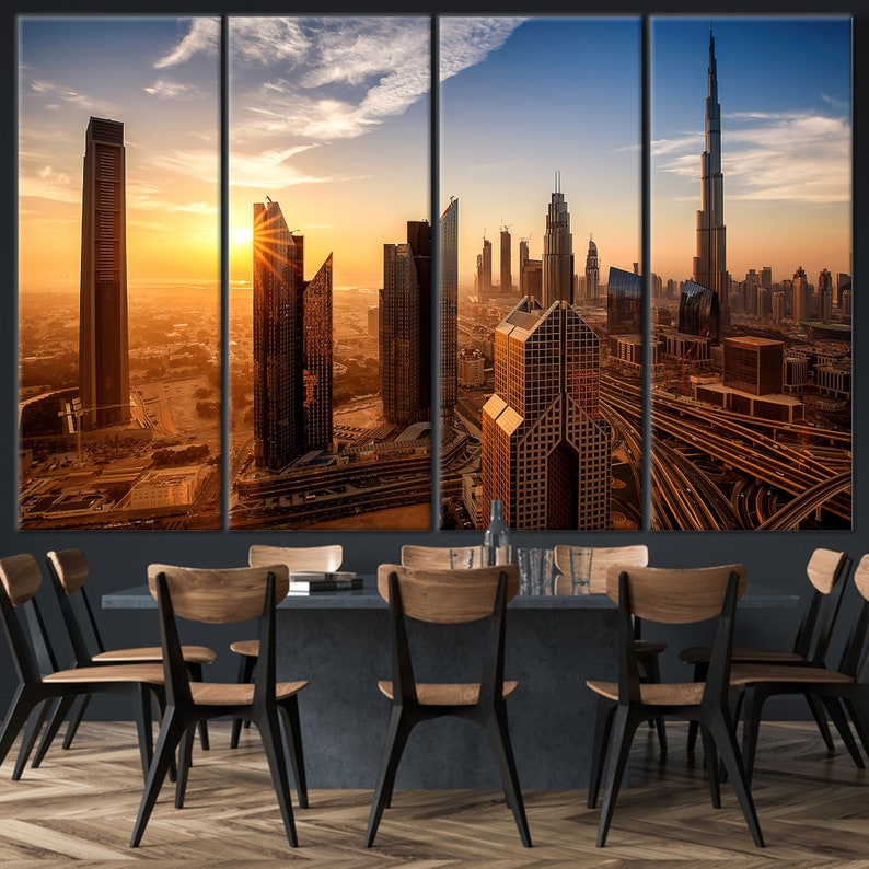 May include: A four-panel canvas print of a cityscape at sunset. The image shows modern skyscrapers, including the Burj Khalifa, bathed in a warm, golden light. The artwork is displayed above a dining table with wooden chairs.