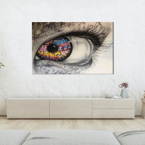 Könnte beinhalten: Ein großes Leinwandkunstwerk mit einem detaillierten Auge mit langen Wimpern. Die Iris ist mit farbenfroher Graffiti-Kunst gefüllt, einschließlich des Textes "HELLO NEW YORK". Das Kunstwerk ist hauptsächlich in Grau- und Weißtönen gehalten, mit lebendigen Farbtupfern.