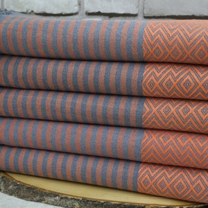 May include: A stack of gray and orange striped towels with a diamond pattern. The towels have a fringed edge.