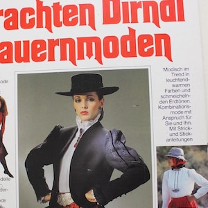 May include: A magazine cover featuring a woman wearing a black jacket and a red and black dirndl skirt. The magazine is titled "Trachten Dirndl Bauernmoden" and features a variety of traditional clothing styles.