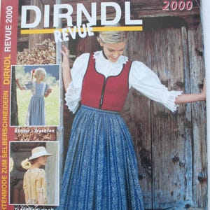 May include: A Dirndl Revue 2000 magazine cover featuring a person wearing a red bodice with a white blouse and a blue patterned skirt. The cover includes smaller inset photos of children's clothing and text detailing sewing patterns for sizes 38-46.
