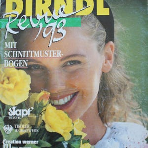 May include: A vintage Dirndl Revue 193 magazine cover from 1993 featuring a person holding a bouquet of yellow roses. The cover includes the text Dirndl Revue 193, Mit Schnittmuster-Bogen, Stapf Textil, Tiroler Heimatwerk, Creation Werner, and Dolisa.