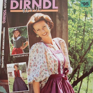 Puede incluir: Una portada de la revista Dirndl Revue de 1995 con una persona que viste una blusa con estampado floral de mangas abullonadas y un delantal liso de color magenta oscuro. La portada incluye textos como Dirndl Revue, Kinder-Dirndl y Trachtenmode zum Selberschneidern.