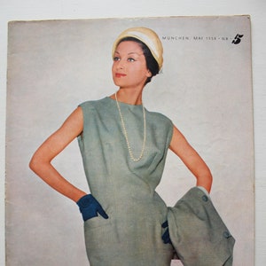 Peut inclure: Une couverture de magazine vintage représentant une femme portant une robe bleu clair et un chapeau blanc. Le magazine s'intitule "Rundschau" et est un magazine de mode allemand pour femmes.