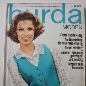 Könnte beinhalten: Ein Magazincover mit einer Frau, die eine blaue Weste über einer weißen Spitzenbluse trägt. Das Magazin heißt "burda MODEN" und hat den Text "Europas größte Modenzeitschrift" unten. Das Cover zeigt auch den Text "3 MARZ 1968".