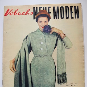 May include: A vintage magazine cover featuring a woman wearing a grey dress and a brown hat. The magazine is titled "Vobachs Neue Moden" and has the text "5. JAHRGANG HEFT Nr. 2/53 PREIS: DM 1,50" on the bottom right corner.
