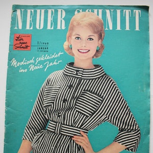 Könnte beinhalten: Ein Vintage-Magazincover mit einer Frau, die ein schwarz-weiß gestreiftes Kleid und einen schwarzen Gürtel trägt. Das Magazin heißt "Neuer Schnitt" und der Text auf dem Cover lautet "Modisch gekleidet ins Neue Jahr", was übersetzt "Modisch gekleidet ins Neue Jahr" bedeutet.