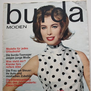 Könnte beinhalten: Ein Vintage-Magazincover mit einer Frau in einem weißen und schwarzen Polka-Dot-Kleid mit einem roten Rosenstrauß. Das Magazin heißt "burda MODEN" und der Covertext lautet "Modelle für jedes Urlaubsziel" und "Die interessanteste Frau des Jahrhunderts: Coco Chanel".