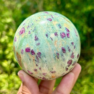 Peut inclure: Une sphère verte et rose avec un motif moucheté. La sphère est faite de rubis dans la zoïsite, également connue sous le nom de rubis dans la kyanite.