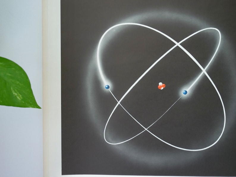 May include: An artistic depiction of an atom, featuring a dark gray background with white orbital paths. Two blue spheres and a cluster of red and white spheres represent atomic components. The image has a scientific or educational theme.
