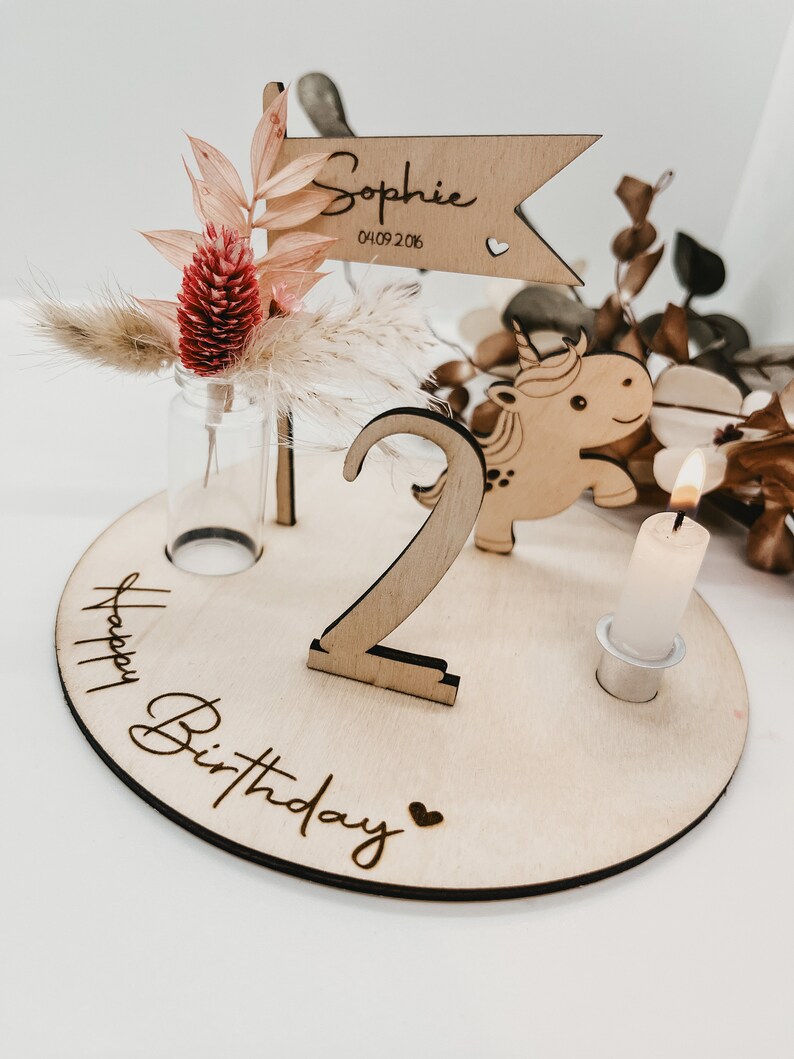 Pu&ograve; includere: Decorazione per compleanno in legno con un unicorno, il numero due, un piccolo vaso con fiori secchi, una candela e il testo "Happy Birthday" e "Sophie 04.09.2016".