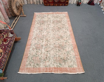 May include: A vintage floral patterned rug with a cream background, pink and green floral designs, and a peach-colored border.