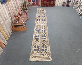 Peut inclure: Un tapis long et étroit avec un motif géométrique dans les tons de bleu, jaune et blanc. Le tapis a une frange aux deux extrémités.