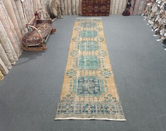 May include: A vintage runner rug with a beige background and a repeating pattern of blue and green floral motifs. The rug has a distressed look and is perfect for adding a touch of bohemian style to any room.