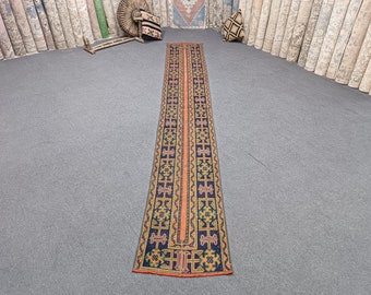 Peut inclure: Un tapis de couloir long et étroit avec un motif géométrique dans des tons d'orange, bleu, vert et noir. Le tapis a un design traditionnel avec des motifs répétés.