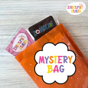 Può includere: Un sacchetto misterioso arancione con pois bianchi, contenente un articolo ZOMBEXIE e una carta rosa e bianca Electra Stein. Le parole "MYSTERY BAG" sono in un fumetto bianco a forma di nuvola.