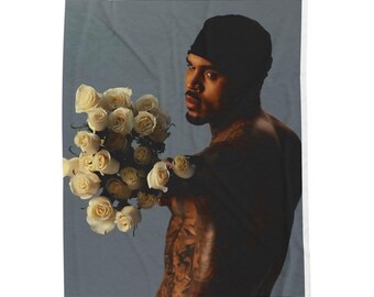 May include: A person holding a bouquet of white roses. The person is wearing a black beanie. The background is a light blue color.