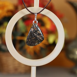 May include: A silver chain necklace with a brown and black stone pendant. The pendant is a triangular shape and has a wire-wrapped bail.