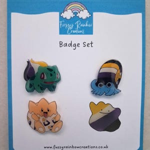 May include: A set of four colourful enamel badges featuring cartoon characters. The badges include a green and yellow creature, a blue snail-like figure, an orange egg-shaped character, and a purple and yellow blob. The text "Badge Set" is displayed.