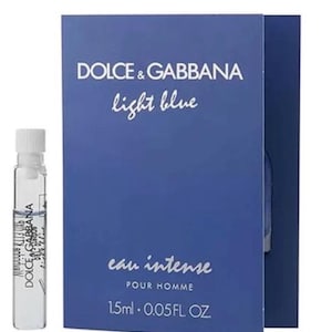 Puede incluir: Un pequeño vial de vidrio transparente de fragancia Dolce & Gabbana Light Blue Eau Intense Pour Homme junto a una tarjeta de muestra de cartón azul. La tarjeta presenta el texto Dolce & Gabbana, light blue, eau intense, POUR HOMME, 1,5 ml y 0,05 FL OZ.