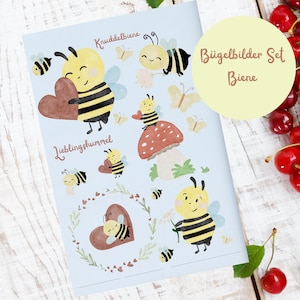 Può includere: Un set di adesivi da stirare a tema ape. Gli adesivi presentano simpatiche api di cartoni animati con cuori, fiori e funghi. Il testo sul foglio recita "Knuddelbiene", "Lieblingshummel" e "Bügelbilder Set Biene".