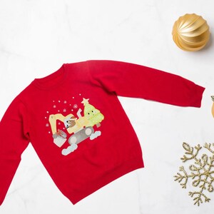 Könnte beinhalten: Roter Weihnachtspullover mit einer Cartoon-Illustration eines Baggers, der einen Weihnachtsbaum trägt. Der Bagger ist gelb und der Baum ist grün. Der Pullover hat ein weißes Schneeflockenmuster.
