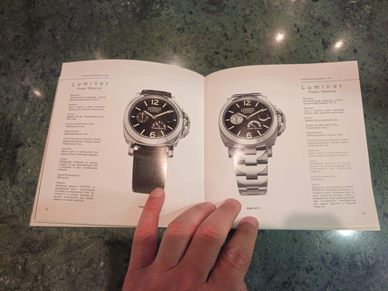 Pu&ograve; includere: Due orologi da polso con quadrante nero, dettagli argentati e cinturini in pelle nera. L'orologio a sinistra ha un cinturino in pelle nera e l'orologio a destra ha un cinturino in metallo argentato. Entrambi gli orologi hanno la scritta "Luminor" stampata sul quadrante.