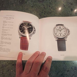 Pu&ograve; includere: Due orologi da polso con cinturini in pelle nera. L'orologio a sinistra ha un quadrante nero con numeri e lancette bianchi. L'orologio a destra ha un quadrante bianco con numeri e lancette neri. Entrambi gli orologi hanno le parole "Luminor Marina" sul quadrante.