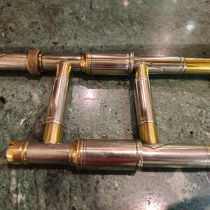 May include: Close-up of the inner workings of a trombone, showing the gold-plated brass tubing and the silver-plated brass slides.