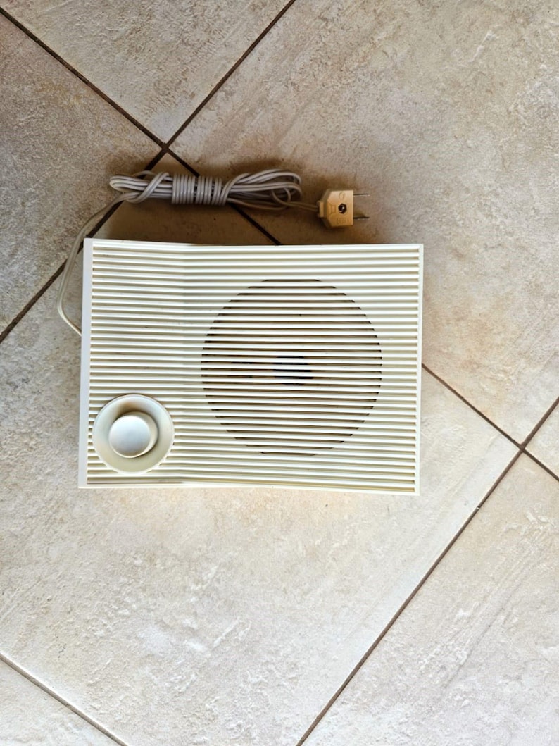 May include: A white vintage radio with a single speaker and a round knob. The radio has a cord with a plug.