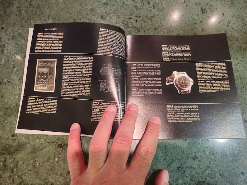 Pu&ograve; includere: Un libro bianco e nero aperto a una pagina con una cronologia di orologi Rolex. La pagina presenta un'illustrazione in bianco e nero di un orologio e una foto di un orologio Rolex argentato con quadrante nero.