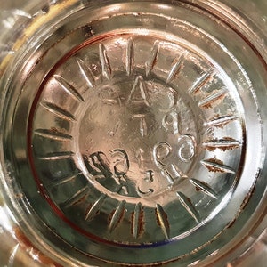 May include: Close-up of the bottom of a clear glass bottle with a circular embossed design and the text "PAT. 1909" inside the circle.