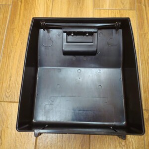 Może przedstawiać: Czarny plastikowy pojemnik do przechowywania o prostokątnym kształcie z pokrywką na zawiasach. Pojemnik ma mały prostokątny otw&oacute;r na g&oacute;rze.