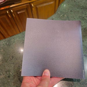 Pu&ograve; includere: Un foglio di carta vetrata grigia con il testo "P400 07109" stampato sul lato.