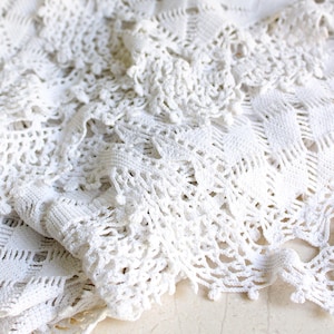 May include: White crocheted tablecloth with a delicate pattern and a ruffled edge.
