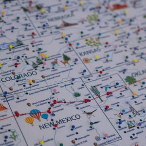 Close-up of USA travel map with push pins marking various locations in Colorado, Kansas, New Mexico, and Oklahoma. Illustrated landmarks and national parks for travelers. Personalized map on canvas for travel, tracking and home decor.