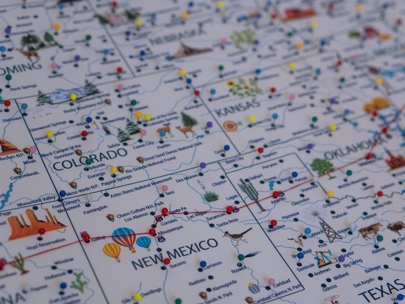 Close-up of USA travel map with push pins marking various locations in Colorado, Kansas, New Mexico, and Oklahoma. Illustrated landmarks and national parks for travelers. Personalized map on canvas for travel, tracking and home decor.