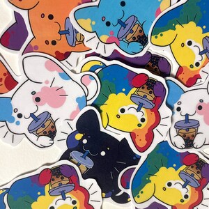 May include: A collection of colorful stickers featuring cartoon characters with a drink. The stickers have a white outline and are in various colors, including orange, blue, white, and black. Each character is drinking a bubble tea.