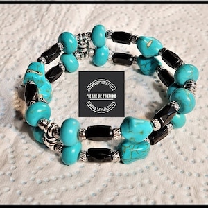 Puede incluir: Un brazalete de cuentas turquesa y negras con detalles plateados. El brazalete está hecho de piedras turquesa, cuentas negras y separadores plateados. El brazalete es de doble fila y tiene un cierre de broche.