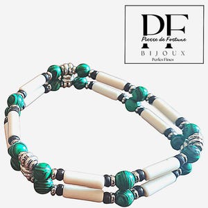 Peut inclure: Un bracelet à double rangée composé de perles cylindriques blanches, entrecoupées de perles de malachite vertes et d'éléments argentés. Ce bijou présente un design en pierres naturelles. Le logo de la marque "DF Pierre de Fortune Bijoux Perles Fines" est en haut à droite.