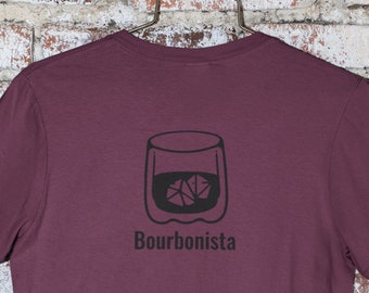 Puede incluir: Una camiseta de color granate con un gráfico negro de un vaso de bourbon con cubitos de hielo y el texto "Bourbonista" impreso en la espalda.