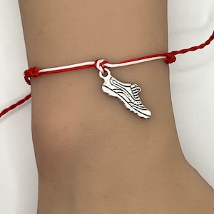 May include: Red and white string bracelet with a silver shoe charm.