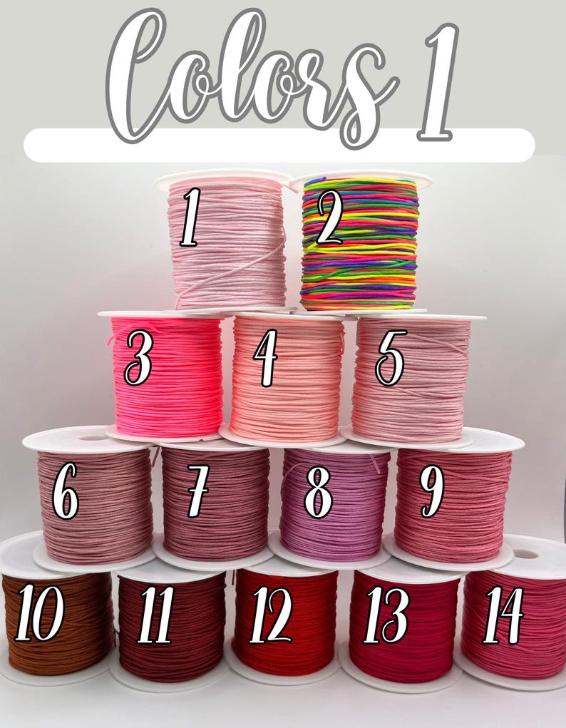 Puede incluir: Carretes de cord&oacute;n colorido en varios tonos, incluyendo rosa, rojo y marr&oacute;n. La imagen est&aacute; etiquetada como "Colors 1" y presenta carretes numerados, ideales para manualidades o bisuter&iacute;a. El cord&oacute;n est&aacute; bien enrollado en carretes blancos.