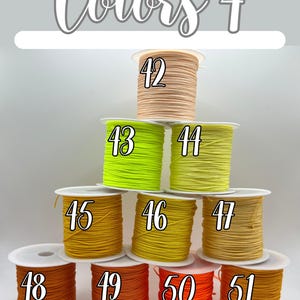 Puede incluir: Imagen titulada "Colores 4" que muestra carretes de cord&oacute;n colorido. Los carretes est&aacute;n numerados del 42 al 51, con colores que van del beige al naranja. El cord&oacute;n est&aacute; bien enrollado en carretes blancos, ofreciendo una variedad de opciones.