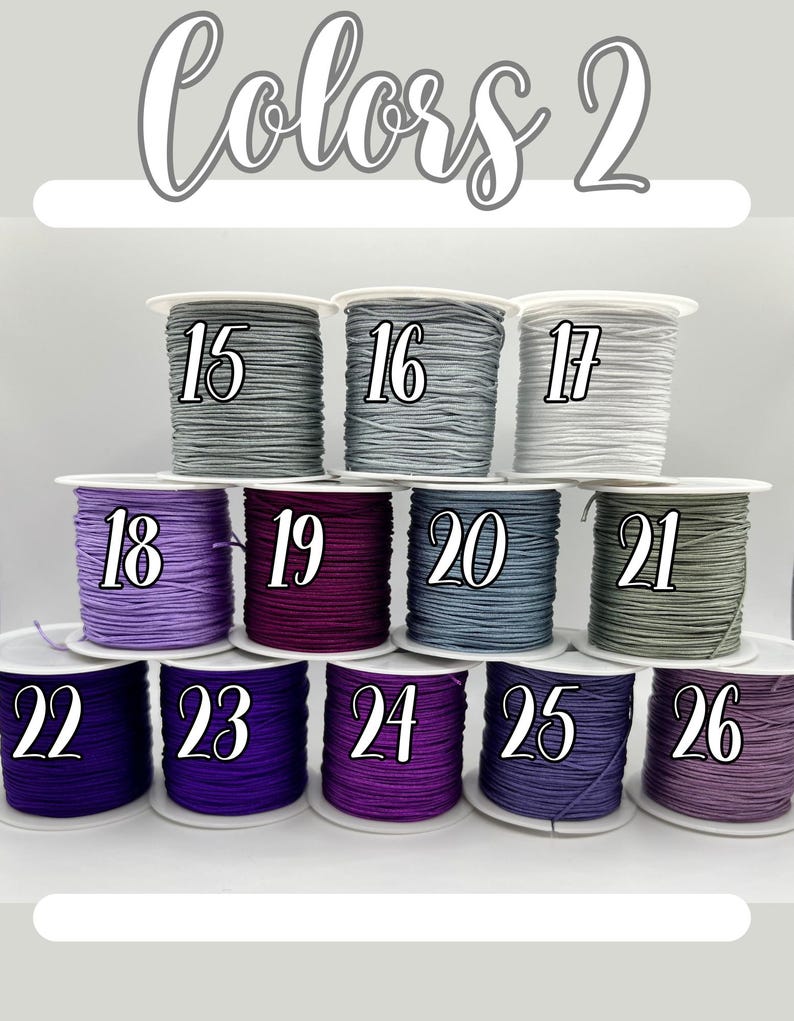 Puede incluir: Una selecci&oacute;n de carretes de cord&oacute;n de colores, cada uno numerado del 15 al 26. Los cordones son de varios tonos de gris, morado y verde. El texto "Colors 2" est&aacute; en la parte superior.