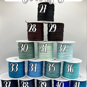 Puede incluir: Una exhibici&oacute;n de carretes de cord&oacute;n en varios colores, numerados del 27 al 41. Los colores incluyen negro, burdeos, marr&oacute;n, verde, azul y turquesa. El texto "Colors 3" est&aacute; en la parte superior.