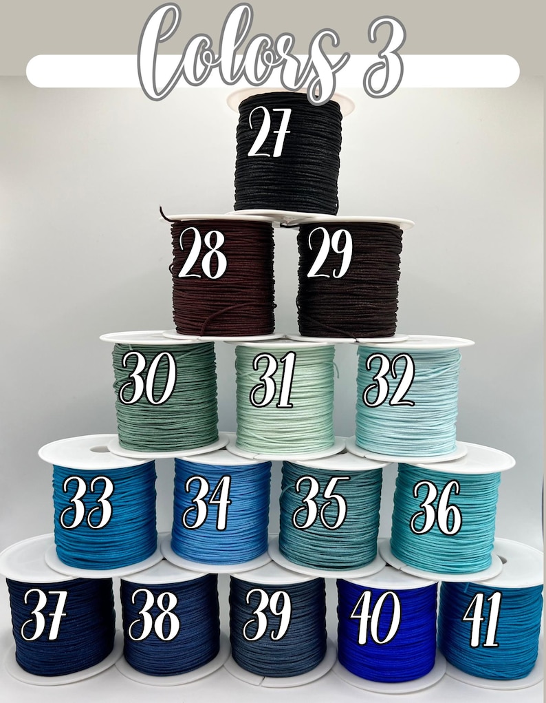 Puede incluir: Una exhibici&oacute;n de carretes de cord&oacute;n en varios colores, numerados del 27 al 41. Los colores incluyen negro, burdeos, marr&oacute;n, verde, azul y turquesa. El texto "Colors 3" est&aacute; en la parte superior.